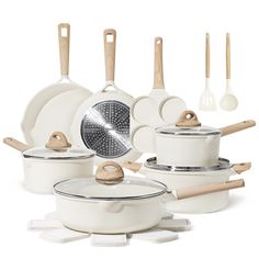 an assortment of white pots and pans with wooden spoons