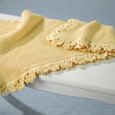 a yellow knitted blanket sitting on top of a white table next to a blue wall