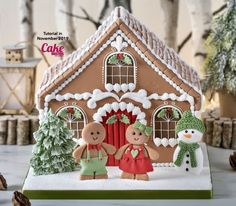 a gingerbread house with two people standing in front