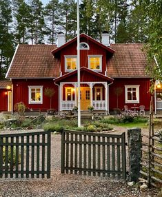 a red house with white trim and two story windows on the front, surrounded by trees