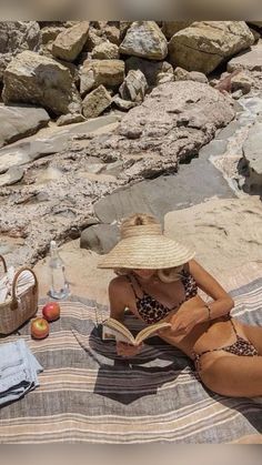 a woman sitting on the beach reading a book