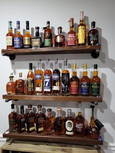 several shelves filled with liquor bottles on top of wooden shelves next to a white wall