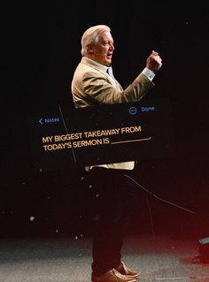 a man standing in front of a screen giving a speech