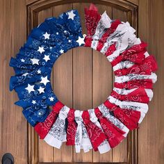 a patriotic wreath with red, white and blue fabric on it hanging on a door