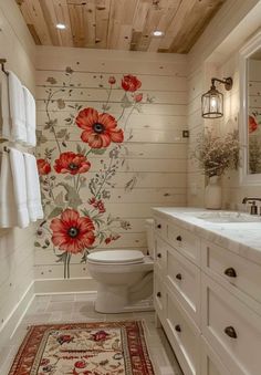 a bathroom decorated in white with red flowers on the wall and wooden flooring, along with a rug