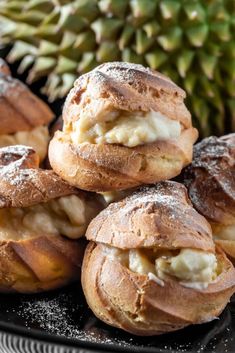 several pastries on a black plate with pineapple in the backgroung