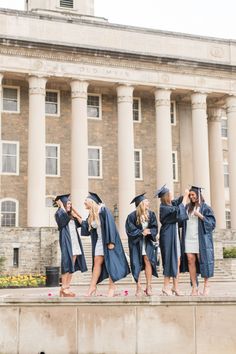 a group of people standing in front of a building with graduation caps and gowns