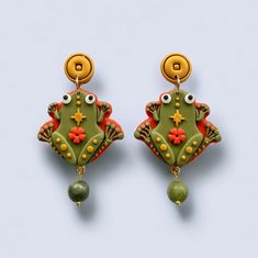 🐸 Welcome prosperity and good fortune this Lunar New Year with our exquisite Money Frog Earrings, a symbol of abundance in Asian cultures. These earrings uniquely combine the traditional money frog motif with elegant, modern design elements. At the top of each earring is a beautifully crafted gold coin shape, representing wealth and good luck. This coin seamlessly transitions into the main attraction - a detailed money frog, known for its mythical powers to attract prosperity and positive energ Symbolic Green Jewelry For Good Luck, Chinese New Year Earrings, Chinese Frog Art, Frog Clay Charm, Feng Shui Money Frog, Chinese Frog Button, Feng Shui Money, Frog Jewelry, Lunar Year