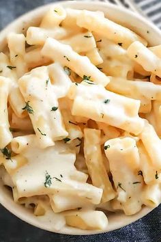 a white bowl filled with macaroni and cheese on top of a blue table cloth