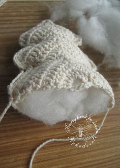 a white knitted hat sitting on top of a wooden table next to cotton floss