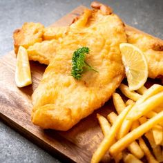 fish and fries on a cutting board with dipping sauce