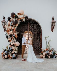 a bride and groom standing in front of a decorated arch