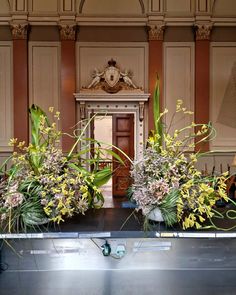 two vases filled with flowers sitting on top of a metal table in front of a doorway