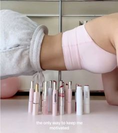 a woman in pink panties is bending over with her legs on the counter next to several lipstick tubes