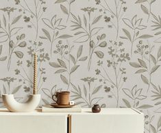 a white cabinet with a vase on top of it next to a flower wallpaper