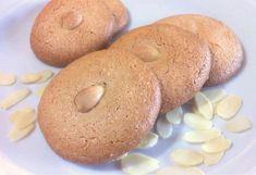 three cookies are sitting on a plate with almonds scattered around them and one cookie has been cut in half