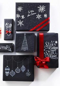 christmas presents are wrapped in black paper with red ribbon and handwritten words on them