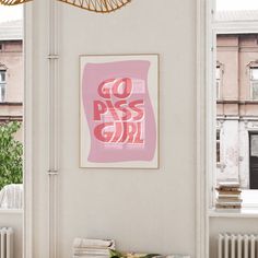 a pink painting hanging on the wall next to a table with books and magazines in front of it