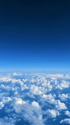 the view from an airplane looking down on clouds and blue sky with white fluffy clouds