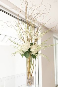 a vase filled with white flowers sitting on top of a table next to a mirror