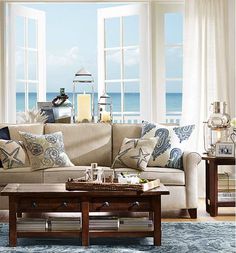 a living room filled with lots of furniture and large windows overlooking the ocean on a sunny day