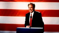 a man standing at a podium in front of an american flag