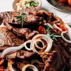 steak, onions and tomatoes on a white plate