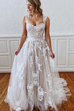 a woman in a wedding dress standing on a wooden floor with her hands behind her back