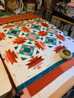 a quilt is laying on top of a table in a room full of books and other items