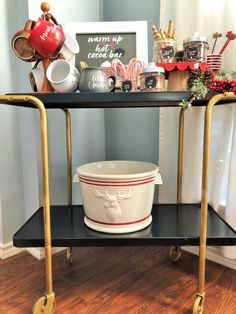 a black and gold serving cart with a white bowl on it, decorated for christmas