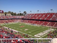 an empty football stadium with red seats and fans in the stands looking out over the field