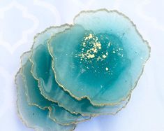 three pieces of blue agate with gold flecks on them sitting on a white surface