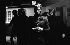 a group of people dressed up in costumes and masks walking down a hallway with one person wearing a mask