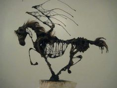 a sculpture of a horse is on display in a room with white walls and flooring