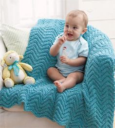 a baby sitting on a couch with a blue blanket