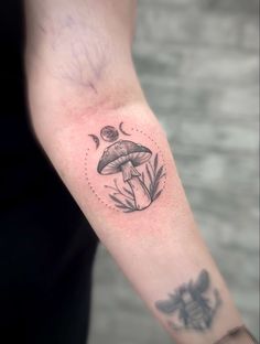 a person with a tattoo on their arm has a small mushroom and leaves in the center