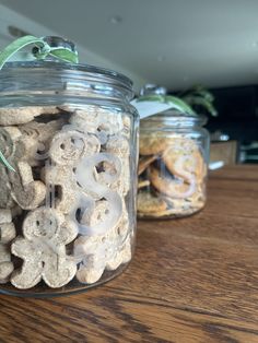 three glass jars filled with cookies on top of a wooden table