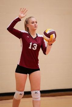 a female volleyball player holding a ball in her hand and blocking it with both hands