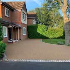 a large driveway in front of a house with trees and bushes on both sides of it