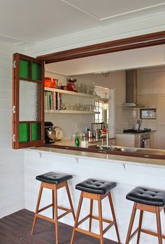 three stools are sitting in front of a bar with an open window on the wall