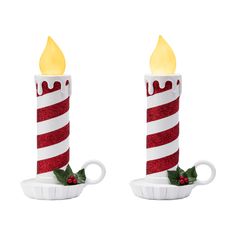 two red and white candles with holly leaves on them, one has a candle in the shape of a cup