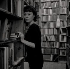 a woman is looking for books in a library