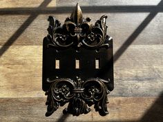 an ornately designed light switch plate on a wood floor with sunlight coming through the window