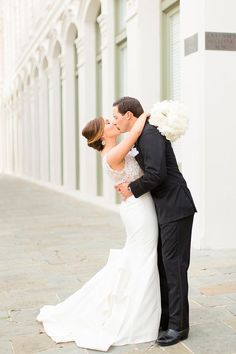 a bride and groom kissing on the street