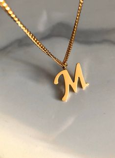 Letter M necklace, set on a stainless steel ,golden color chain. Chain length 19'  With addition cost there is an option to add a white freshwater pearl, as a charm, next to the letter. 6 mm, white round pearl Kindly choose your option. Beautiful spiritual gift. Please make sure you to pay attention to the size of the pendant. I have added pictures next to 25 cent coin, and measurement tape.  Need a different length just write it to me in the "message to the seller" box of the order form. **LIMI Minimalist Personalized Tan Charm Necklaces, Everyday Stainless Steel Initial Necklace, Minimalist Gold Stainless Steel Name Necklace, Minimalist Personalized Tan Charm Necklace, Gold Initial Necklace In Stainless Steel, Gold Stainless Steel Initial Necklace, Minimalist Tan Charm Necklace As Gift, Minimalist Gold Monogram Charm Necklace, Gold Minimalist Initial Necklace In Stainless Steel