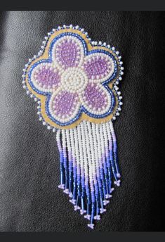 a close up of a piece of cloth with beads on it and a beaded flower