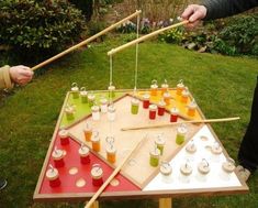 two people standing next to each other near a table with cups and sticks on it