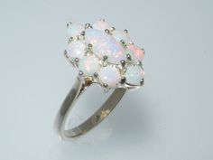 an opalite and diamond cluster ring on a white surface, with the center stone surrounded by smaller opales