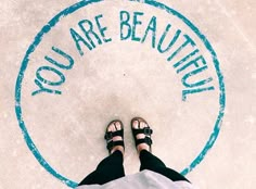 a person standing in front of a sign that says you are beauteed on the ground