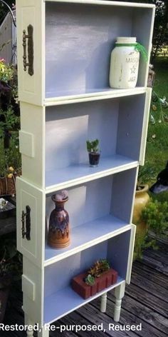 an old bookcase is painted white and has some plants on the top shelf in front of it